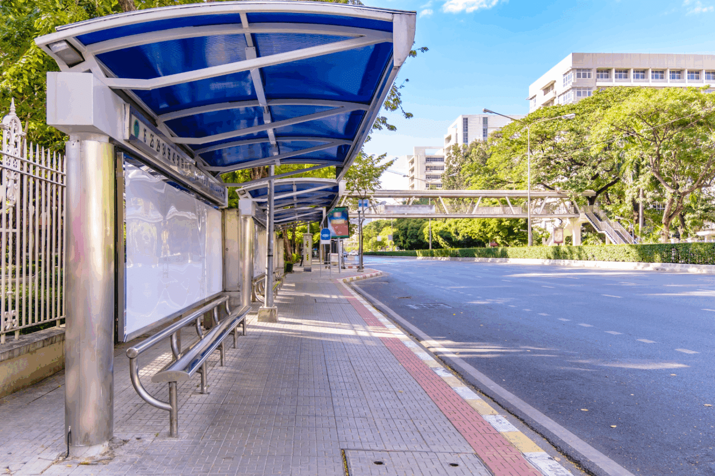 stainless steel cantilever carport with blue roof being used to cover pedestrians at a bus stop
