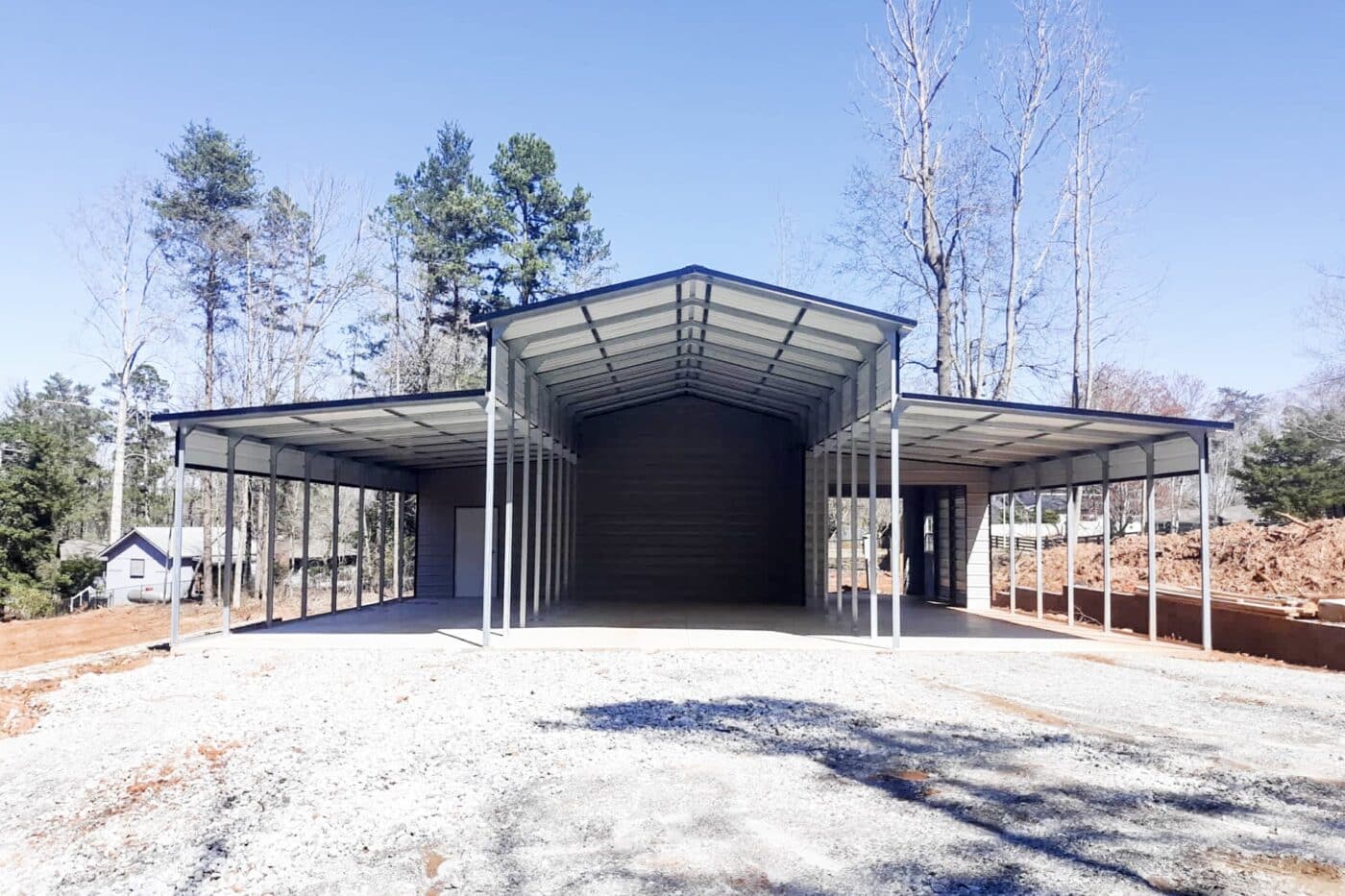 A Eagle style open sided Carport with storage in the back section. left section includes a white door. and the right side includes a garage door.