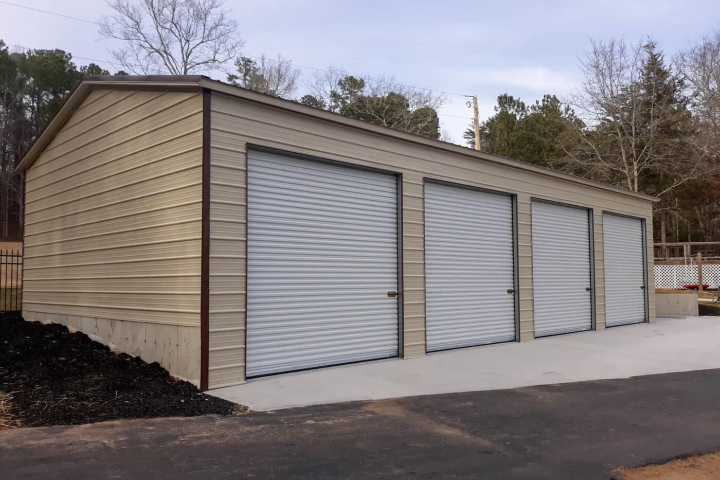 a Custom fully enclosed cream colored carport garage. garage includes four extra tall roll up garage doors.