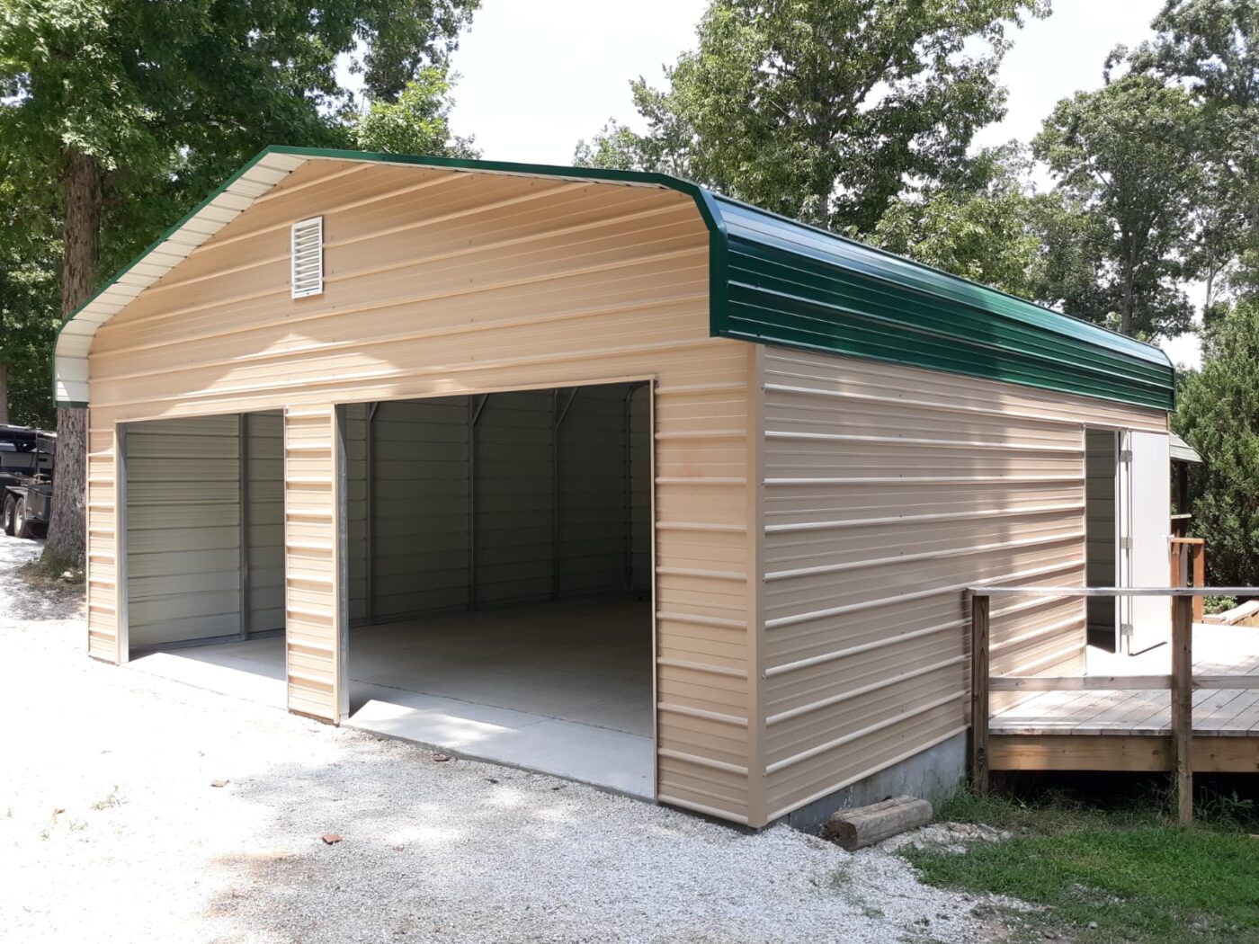 A tan 3 sided enclosed carport with a green capped roof. It includes a side door.