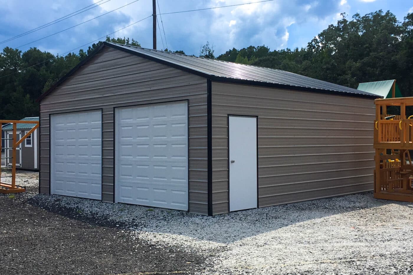 A brown with black roof fully enclosed carport garage. includes two tall white garage doors and a white side door.