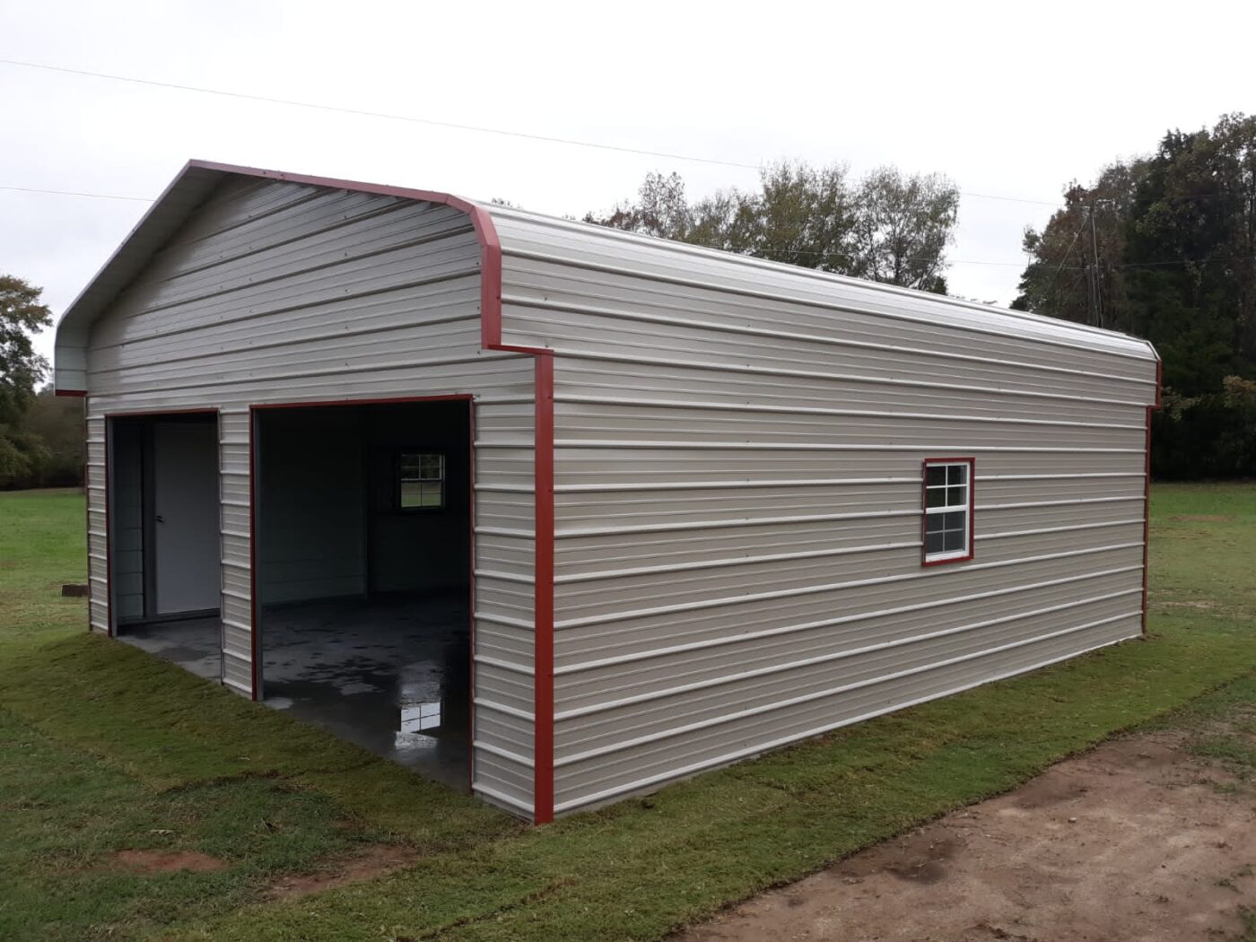 a grey 3 sided enclosed carport with red corner and side window trim.